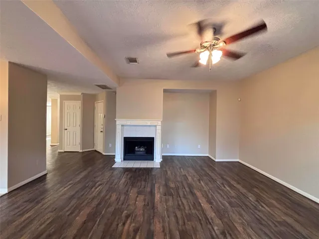 a view of an empty room with wooden floor and a fireplace