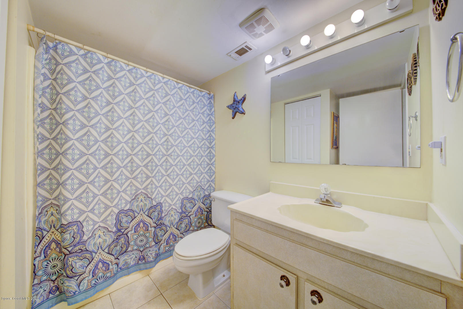 325 Tangle Run Boulevard, Unit 1125 Melbourne, FL 32940 - Photo 17 of 22 a bathroom with a sink a toilet a mirror and shower curtain