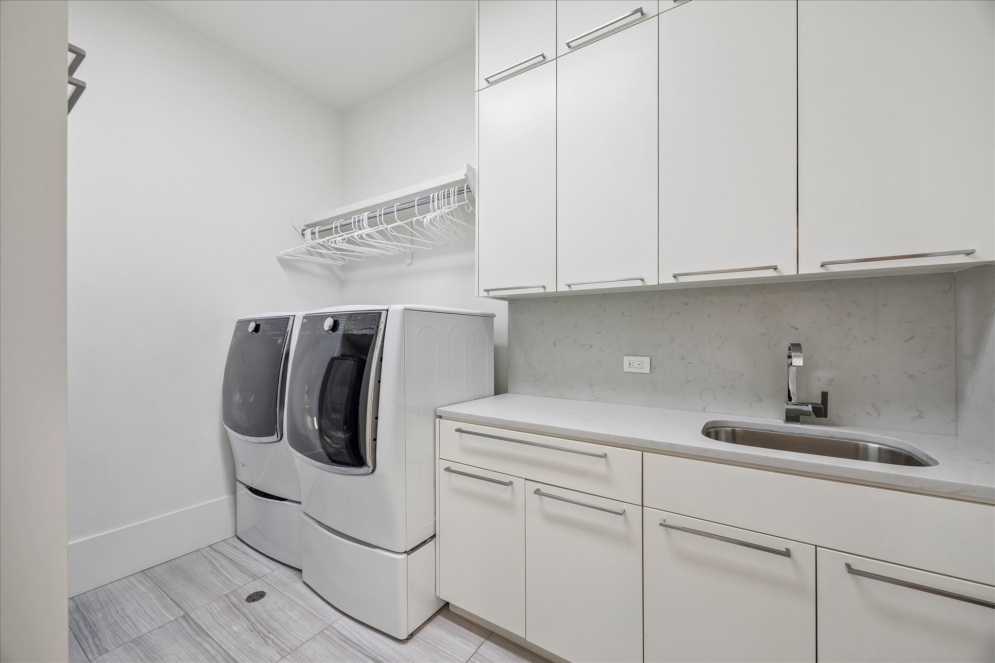 3814 Drake Street Houston, TX 77005 - Photo 44 of 50 This upper-level utility room is well-equipped with custom cabinetry, quartz counters, a sink, a hanging rack and a floor drain.