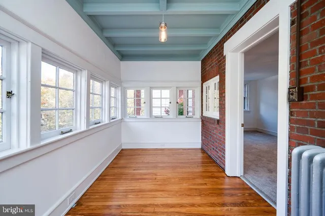a view of an empty room with window and wooden floor
