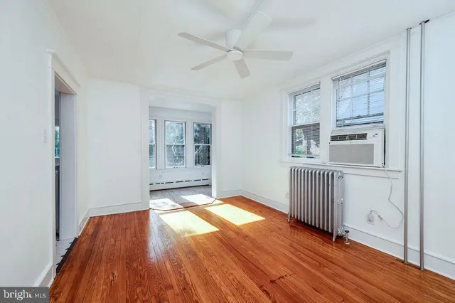 a view of empty room with wooden floor and fan