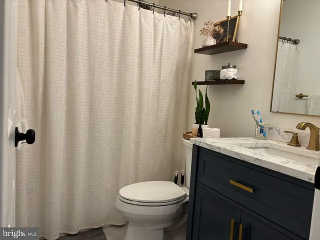 a bathroom with a granite countertop sink toilet and a mirror