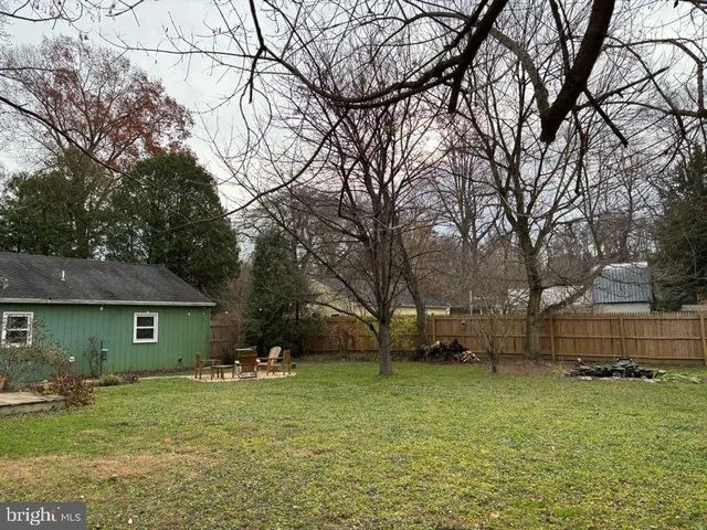 a backyard of a house with wooden fence and a tree