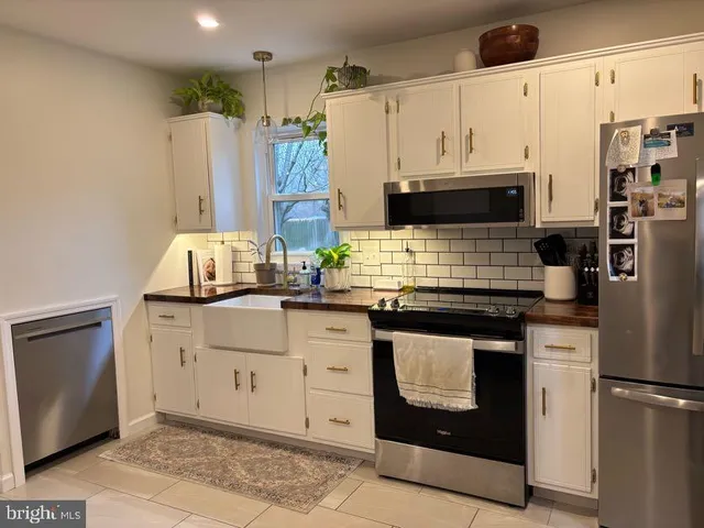 a kitchen with stainless steel appliances a stove a refrigerator a sink and white cabinets