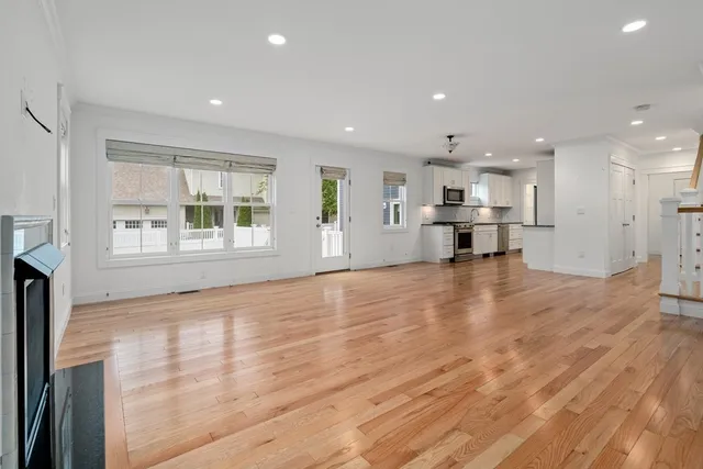a view of empty room with wooden floor and a window