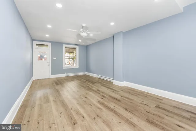 a view of empty room with wooden floor and fan