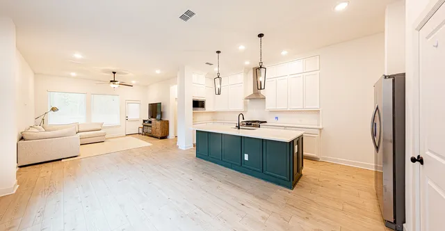 a room with kitchen island a sink stainless steel appliances and cabinets