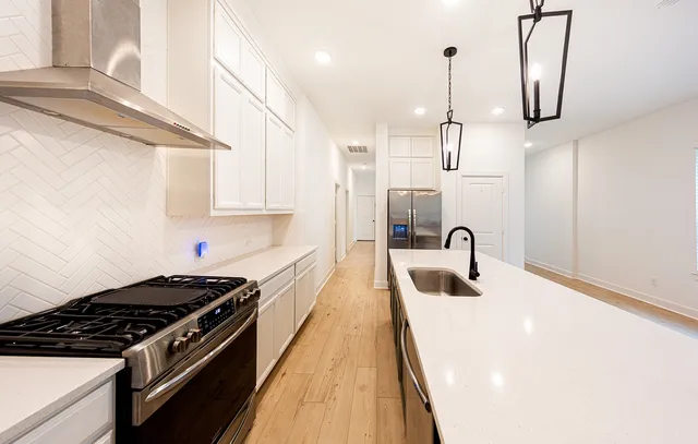 a kitchen with stainless steel appliances a sink a stove and a wooden floors