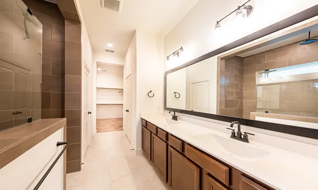 a bathroom with a double vanity sink a mirror and a bathtub