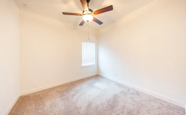 an empty room with a window and a fan