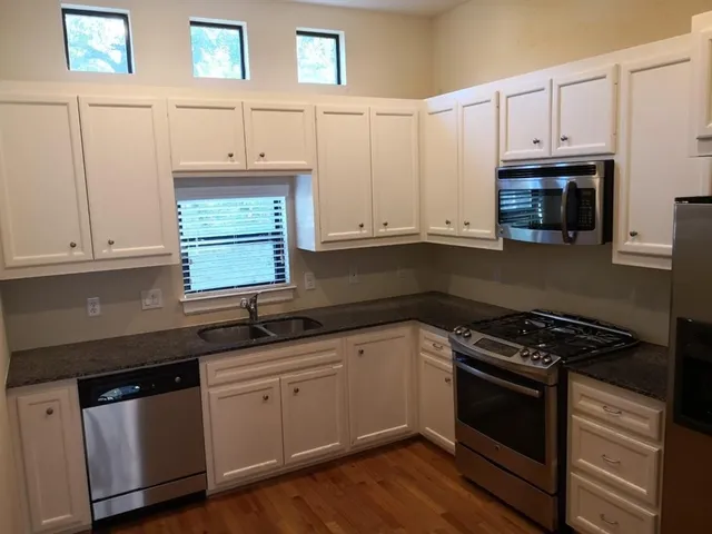 a kitchen with granite countertop white cabinets and a stove a sink