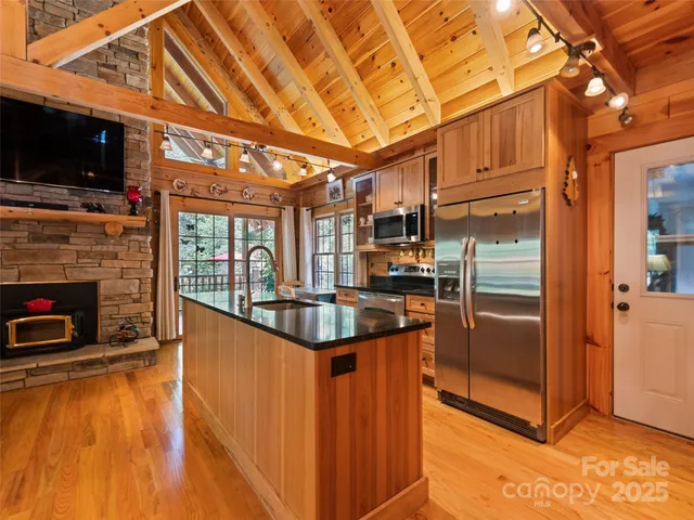 a kitchen with stainless steel appliances granite countertop a refrigerator a stove and a sink with wooden floor