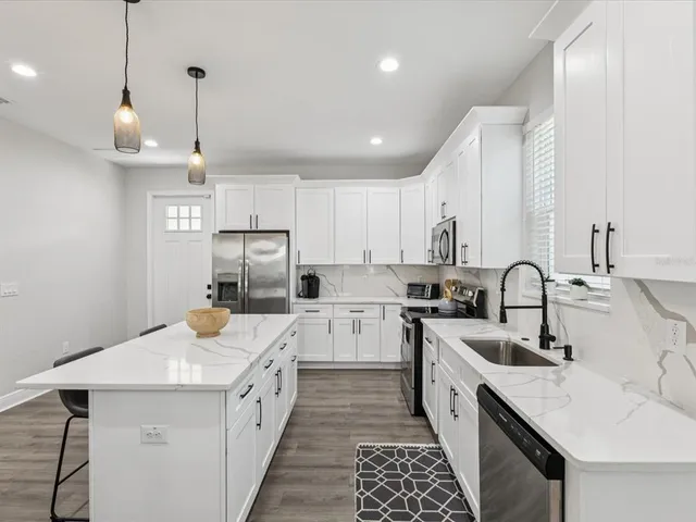 a kitchen with a sink a counter space appliances and cabinets