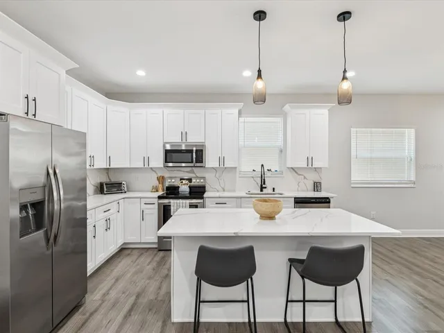 a kitchen with stainless steel appliances granite countertop a sink a stove a dining table and chairs