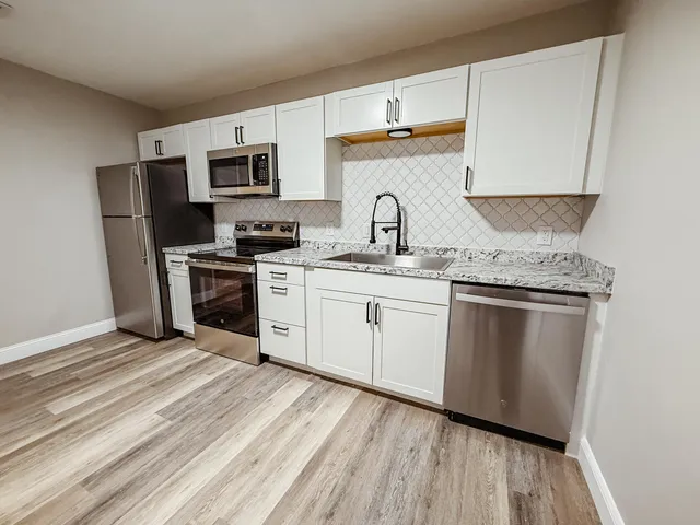 a kitchen with stainless steel appliances granite countertop a stove a sink dishwasher and a refrigerator