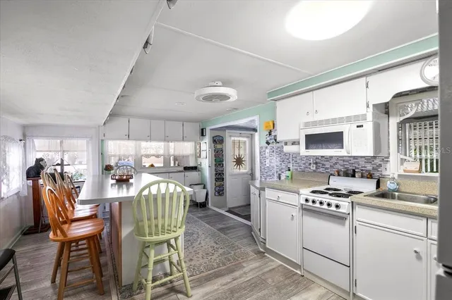 a kitchen with a dining table chairs and white appliances