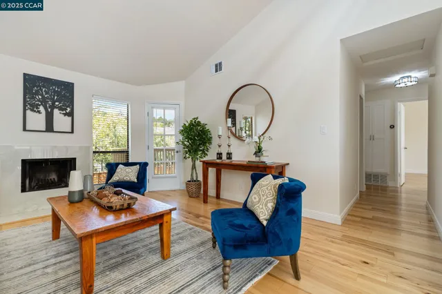 an empty room with wooden floor chandelier fan and windows
