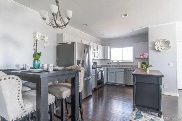 a kitchen with stainless steel appliances granite countertop a table chairs stove and refrigerator