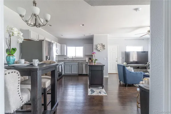 a kitchen with stainless steel appliances granite countertop a sink dishwasher a stove a dining table and chairs with wooden floor