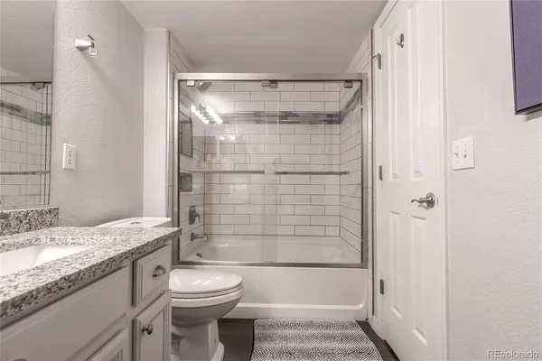 a bathroom with a granite countertop sink toilet and shower