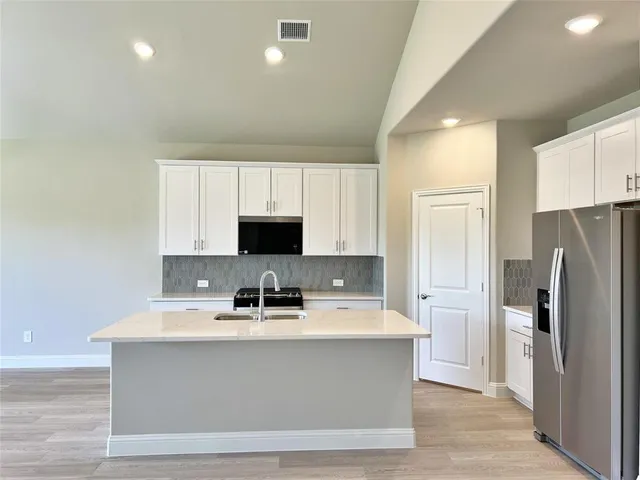 a room with kitchen island a sink stainless steel appliances and cabinets