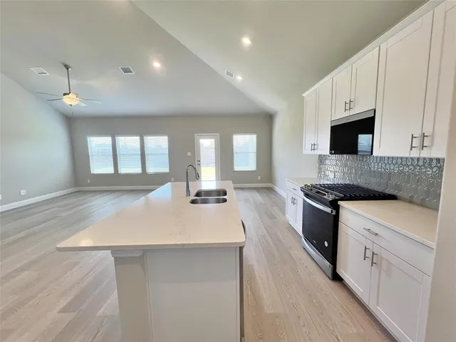 a large kitchen with stainless steel appliances granite countertop a sink a stove and a refrigerator