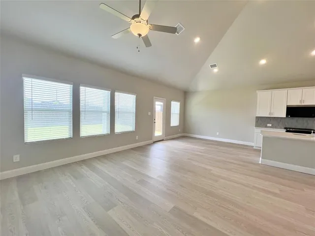 a view of an empty room with a window and wooden floor