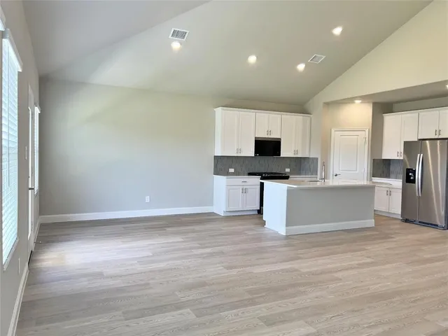 a large kitchen with granite countertop a stove top oven a sink and white cabinets