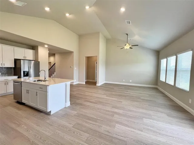 a large room with kitchen island wooden floors wooden cabinets and stainless steel appliances
