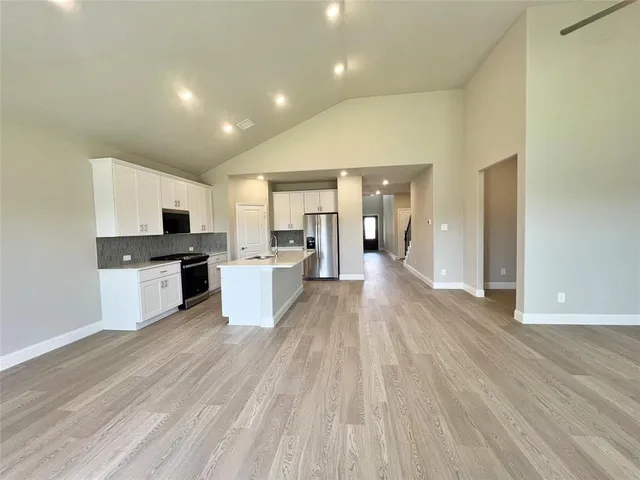 a large kitchen with cabinets wooden floor and stainless steel appliances