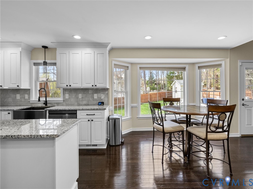 14012 Lippingham Terrace Chester, VA 23831 - Photo 12 of 50 a kitchen with stainless steel appliances granite countertop a stove top oven a sink a dining table and chairs with wooden floor