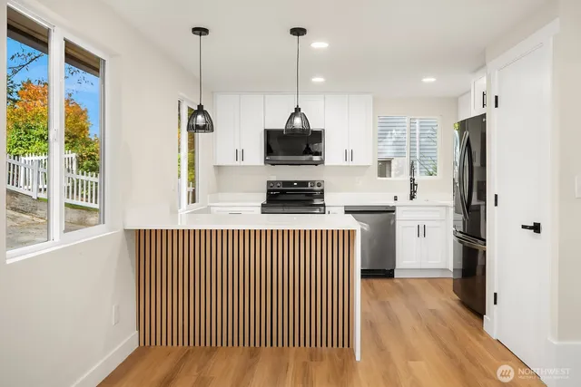 a kitchen with stainless steel appliances granite countertop a refrigerator a sink and white cabinets