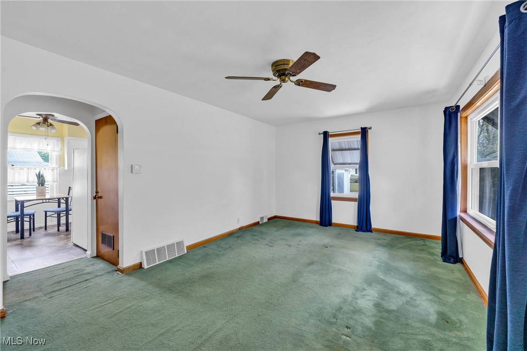 390 Hilliard Road Elyria, OH 44035 - Photo 9 of 30 Unfurnished room featuring ceiling fan, arched walkways, healthy amount of natural light, and carpet