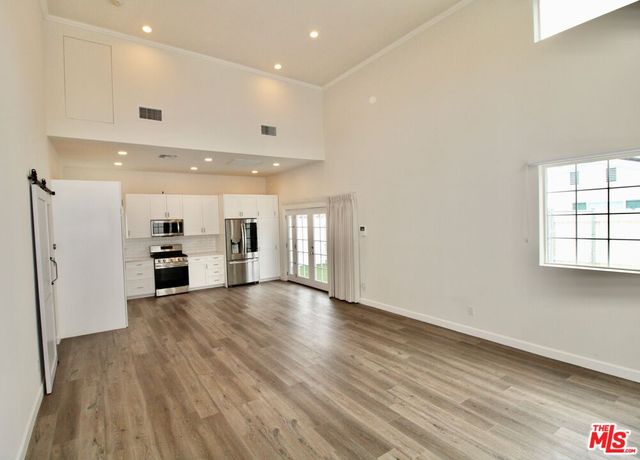 a kitchen with cabinets stainless steel appliances and wooden floor