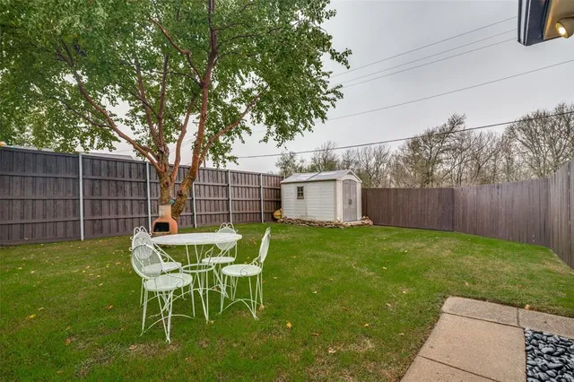 a view of a backyard with table and chairs and a barbeque with wooden fence