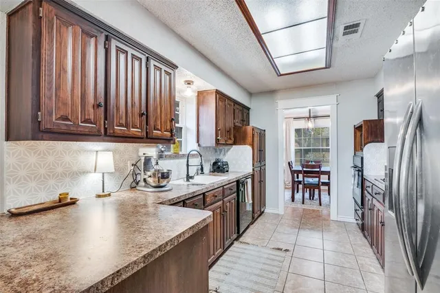 a kitchen with stainless steel appliances granite countertop a refrigerator a sink dishwasher a stove and white countertops with wooden floor