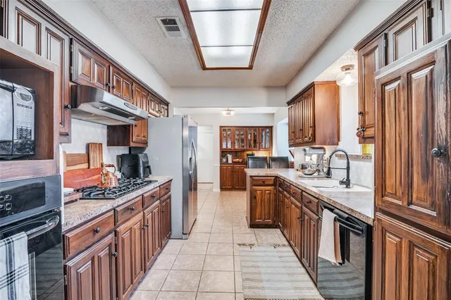 a kitchen with stainless steel appliances granite countertop a stove top oven a sink dishwasher and cabinets with wooden floor
