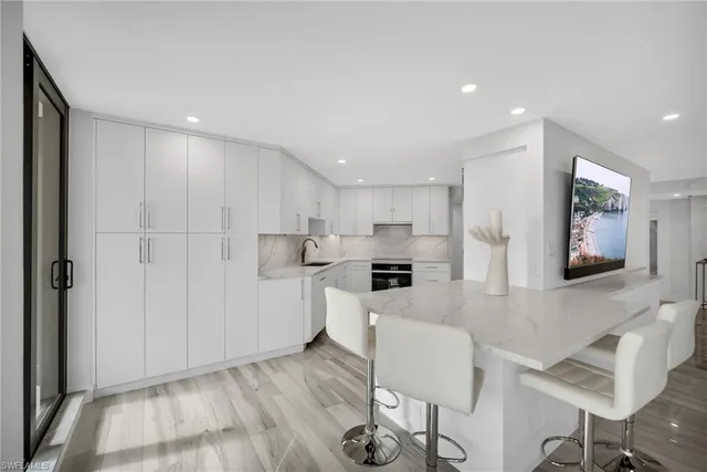 a kitchen with white cabinets and chairs