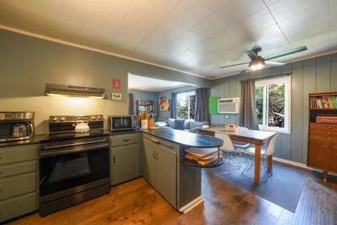 a kitchen with stainless steel appliances a stove a sink dishwasher a dining table and chairs with wooden floor