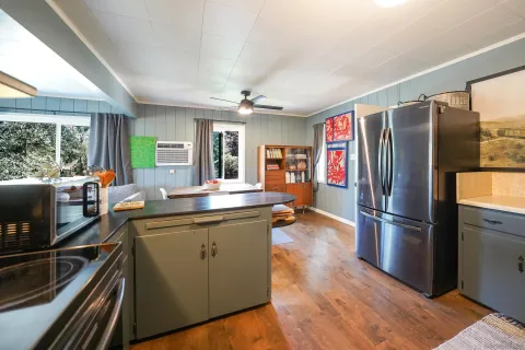 a kitchen with stainless steel appliances granite countertop a refrigerator a sink dishwasher a stove and white countertops with wooden floor