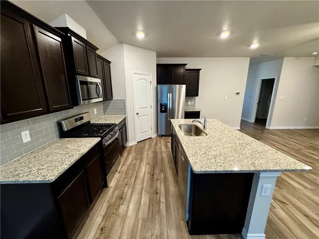 a kitchen with stainless steel appliances granite countertop sink stove top oven and refrigerator