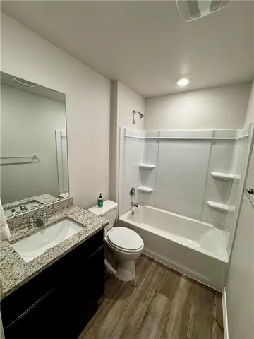 a bathroom with a granite countertop sink toilet a mirror and shower