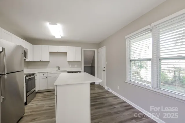 a kitchen with a white cabinets and wooden floor
