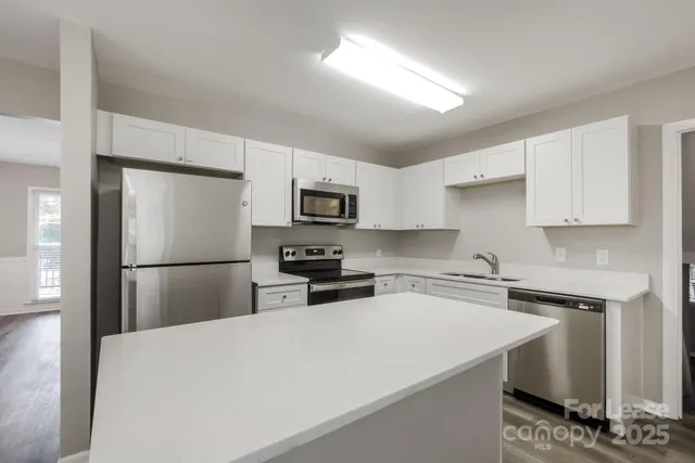 a kitchen with stainless steel appliances a refrigerator a stove a sink a center island and cabinets