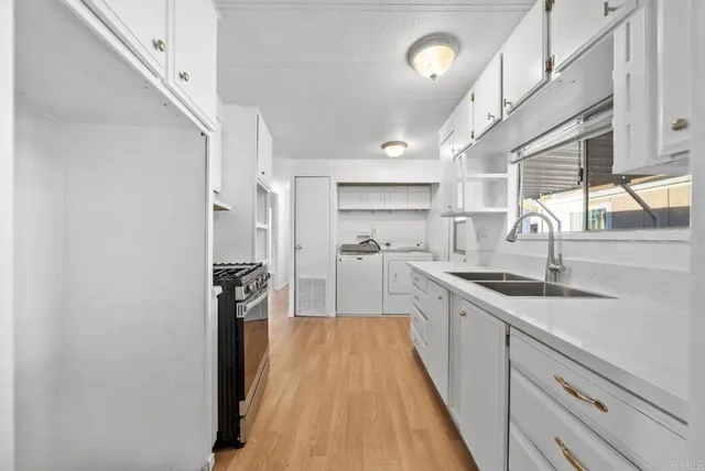 a kitchen with a sink appliances wooden floor and a window
