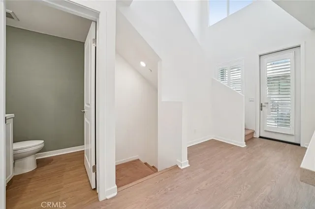 a view of an empty room with wooden floor and a toilet