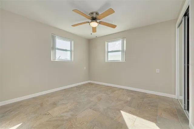 an empty room with windows and ceiling fan