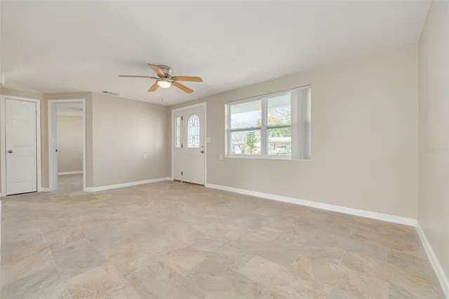 an empty room with windows and ceiling fan