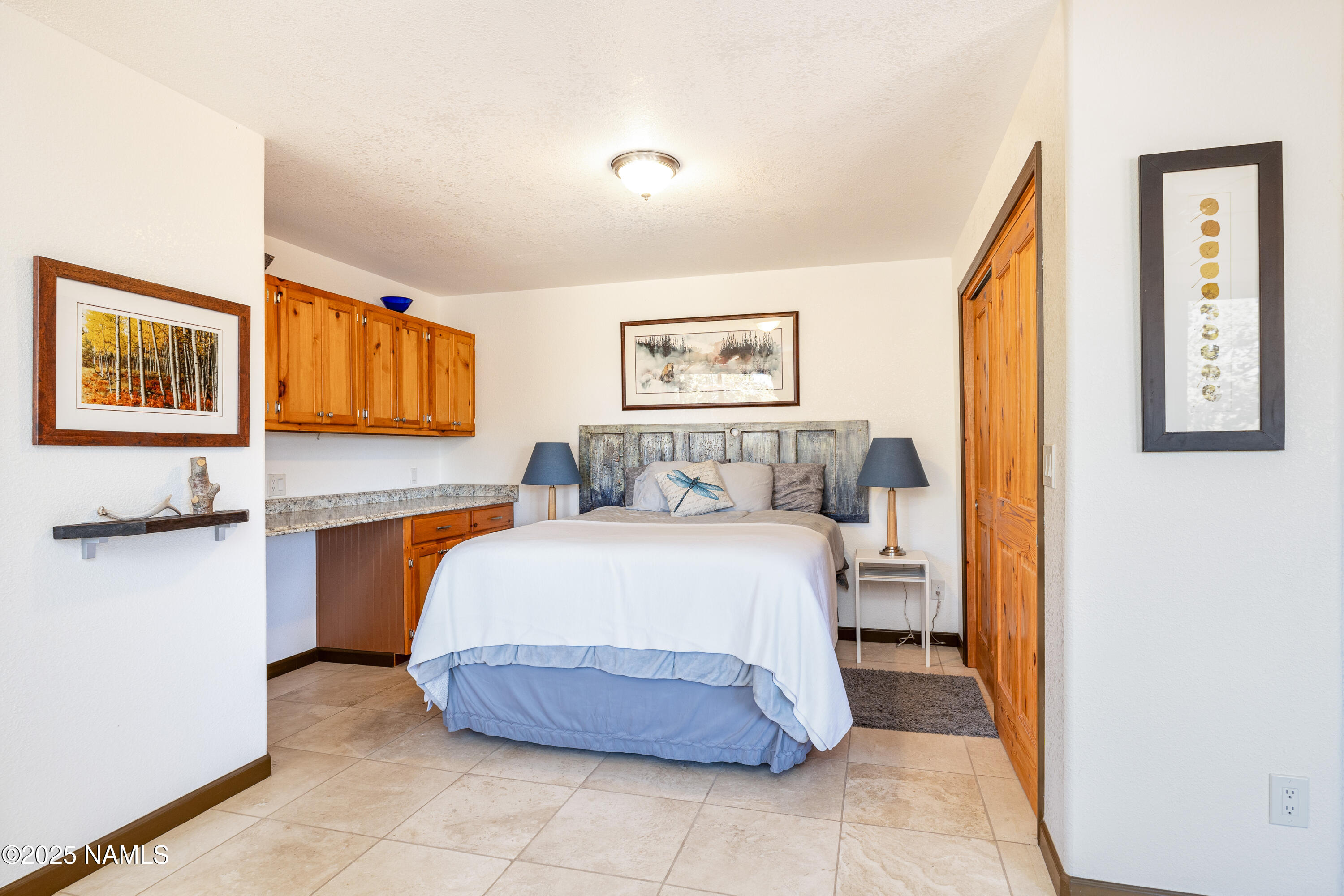 5966 East Camden Road Flagstaff, AZ 86004 - Photo 42 of 70 a spacious bedroom with a bed and painting on the wall