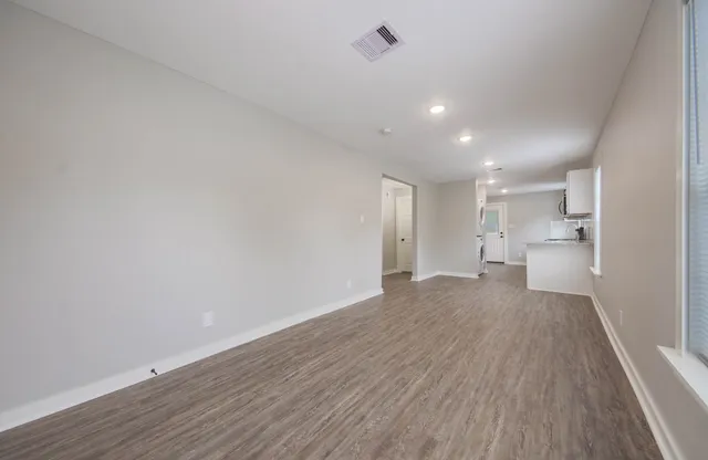 a view of a big room with wooden floor and windows
